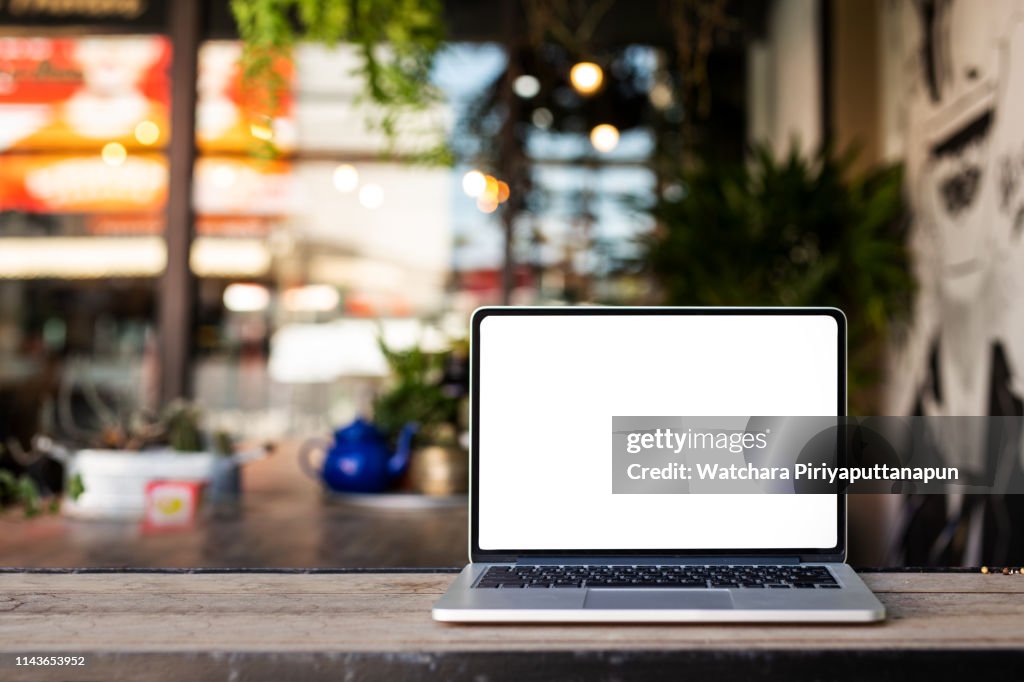 Laptop on the table with coffee shop background. save path.