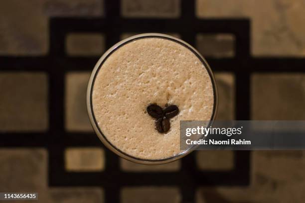 close-up of a frothy espresso martini on a decorative bar table - espresso martini stock-fotos und bilder