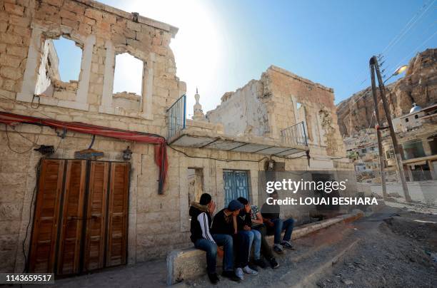 Syrian gather next to a damaged building in the ancient Christian town of Maalula, 56 kilometres northeast of the Syrian capital Damascus, on May 13,...