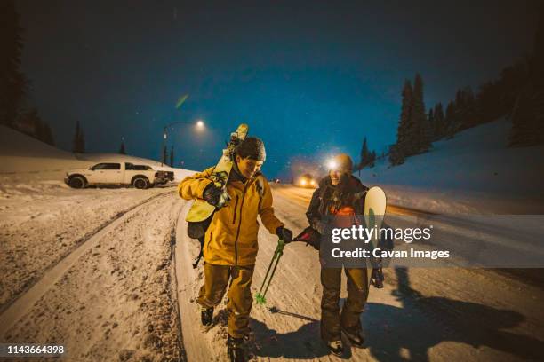 skier and snowboarder make it back to car at end of long ski day - night skiing stock pictures, royalty-free photos & images