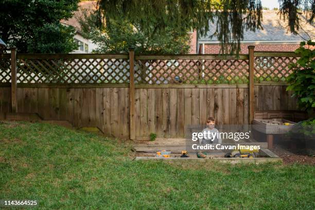 a small boy plays in a sandbox in yard - 1 kid 1 sandbox stock-fotos und bilder