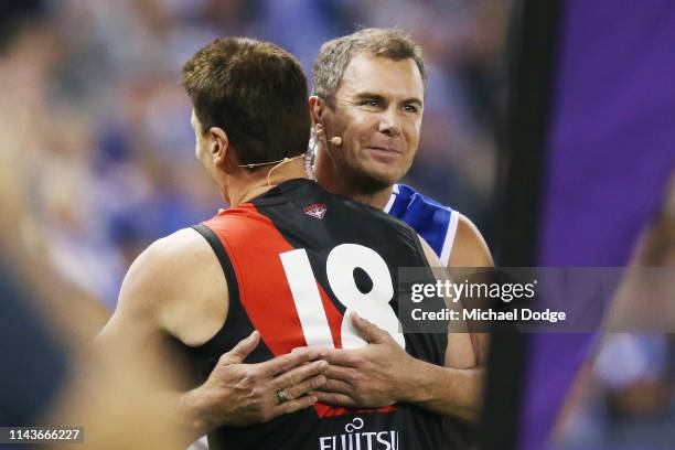 Bombers legend Matthew Lloyd and Kangaroos legend Wayne Carey hug after they take part in the Kick For The Kids fundraiser during the round 5 AFL...