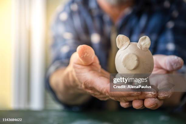 hands holding little piggy bank made by clay - wealth creation stock pictures, royalty-free photos & images