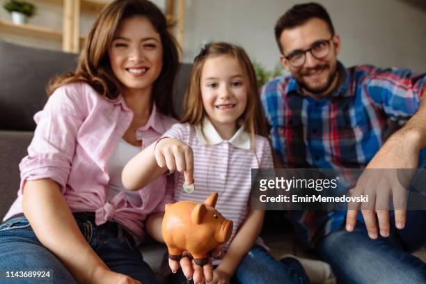 portrait of a family saving money in piggybank - financial wellbeing stock pictures, royalty-free photos & images