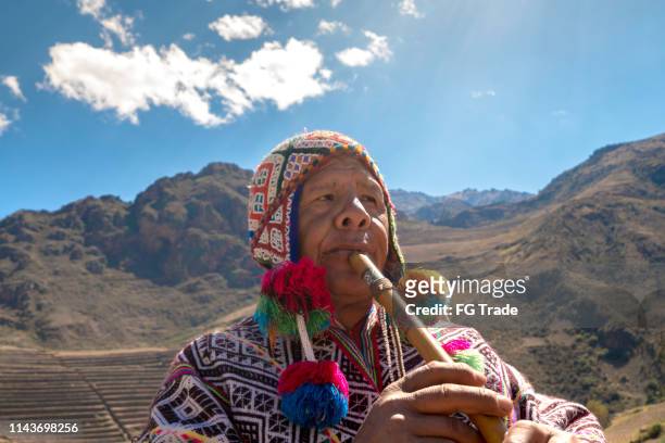 senior man dressing traditional peruvian clothing and playing flute - peruvian culture imagens e fotografias de stock