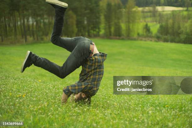 meadow acrobatics. man fooling around - somersault stock pictures, royalty-free photos & images