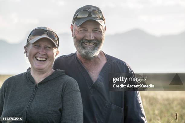 pareja madura sonrisa en la cámara en el campo - farm couple fotografías e imágenes de stock