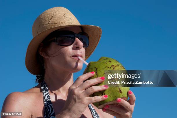 woman drinking coconut water on the beach - coconut water 個照片及圖片檔