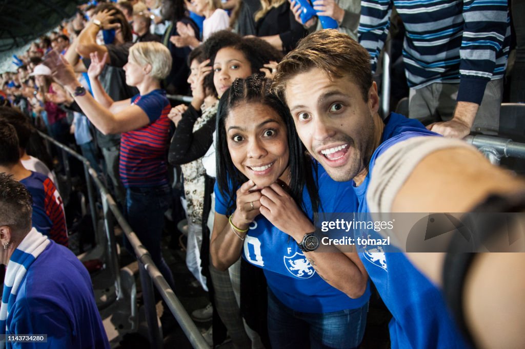 Young couple at footbal match making a selfie
