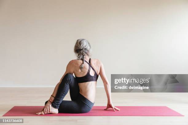 master yoga woman doing half spinal twist, ardha matsyendrasana. - gym fashion stock pictures, royalty-free photos & images