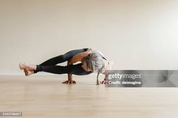 femme de yoga de maître faisant la pose de huit-angle, astavakrasana. - équilibre sur les mains photos et images de collection