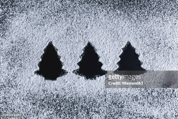 icing sugar on black background, fir trees - puderzucker stock-fotos und bilder