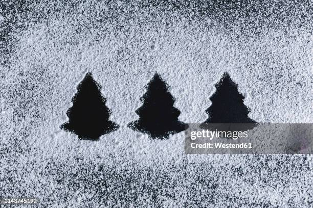 icing sugar on black background, fir trees - poedersuiker stockfoto's en -beelden