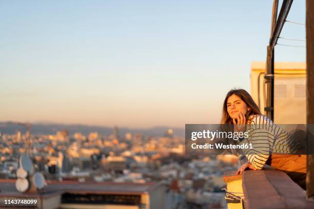 portrait of content young woman relaxing on roof terrace at sunset - woman bending over 個照片及圖片檔