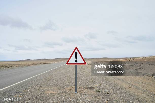 argentina, patagonia, empty road with exclamation mark sign in the middle of desert - ausrufezeichen stock-fotos und bilder