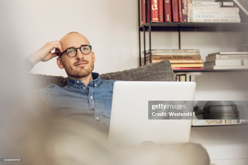 Man sitting on couch, usinag laptop