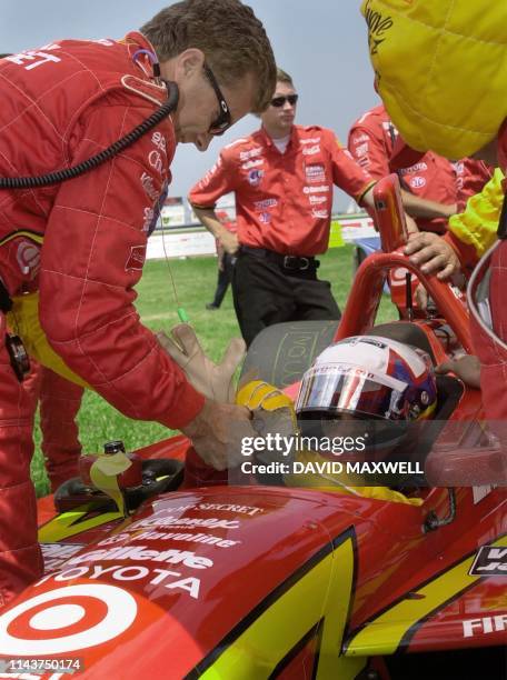 Colombian driver Juan Montoya gets help with his gloves from a member of his crew before the start of the Marconi Grand Prix of Cleveland 02, July,...