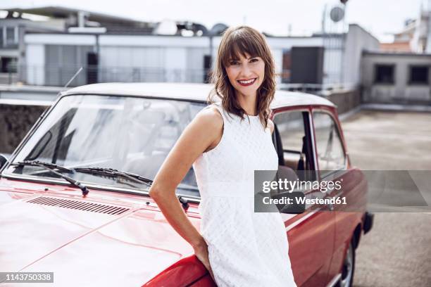 beautiful woman leaning on vintage car - auto stehend stock-fotos und bilder