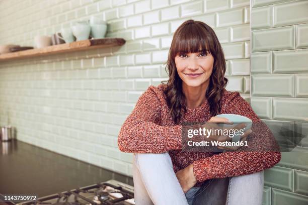 happy woman sitting in kitchen, drinking tea - beautiful woman 40 stock-fotos und bilder