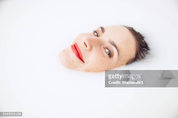 beautiful woman relaxing in a milk bath - milchbad stock-fotos und bilder
