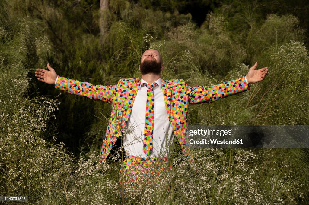Bearded man wearing suit with colourful polka-dots enjoying nature