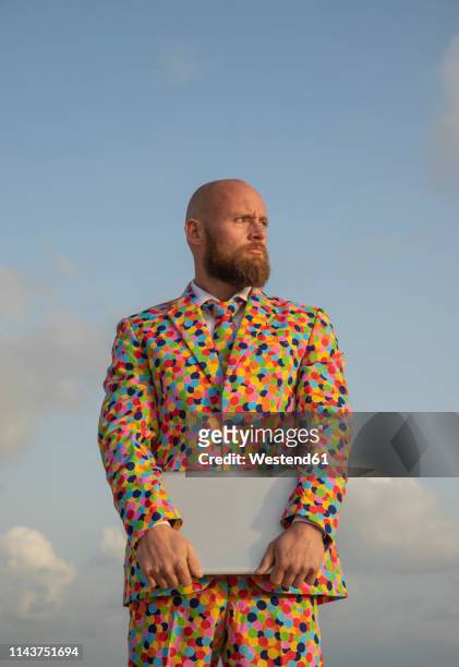 portrait of bald man with beard  wearing suit with colourful polka-dots holding laptop - crazy man computer stock pictures, royalty-free photos & images