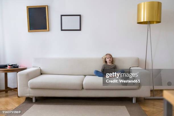 bored girl sitting on the couch at home - child sitting stock-fotos und bilder