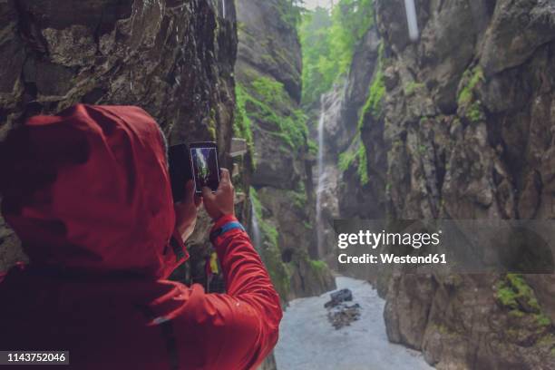 germany, bavaria, partnach gorge near garmisch-partenkirchen, man with red rain jacket taking a photo with smarthone - partnach gorge stock pictures, royalty-free photos & images