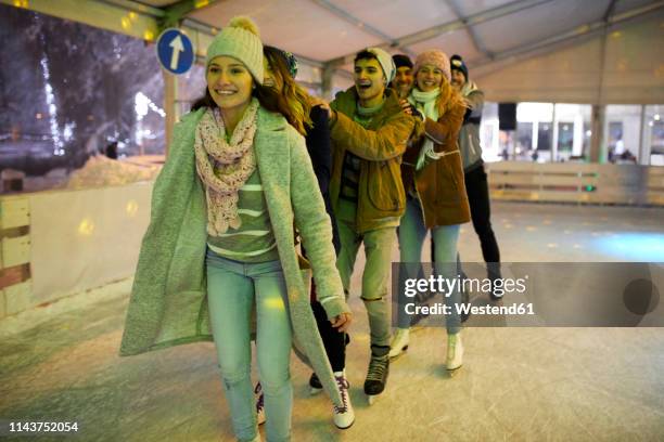 happy friends ice skating on an ice rink at night - conga stock pictures, royalty-free photos & images