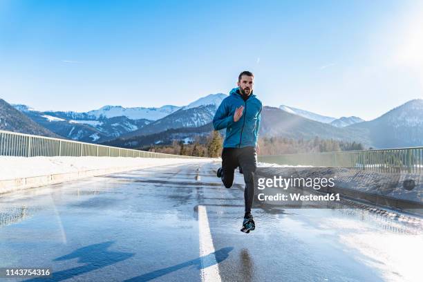 germany, bavaria, sportive man running on a road in winter - winter sport stock-fotos und bilder