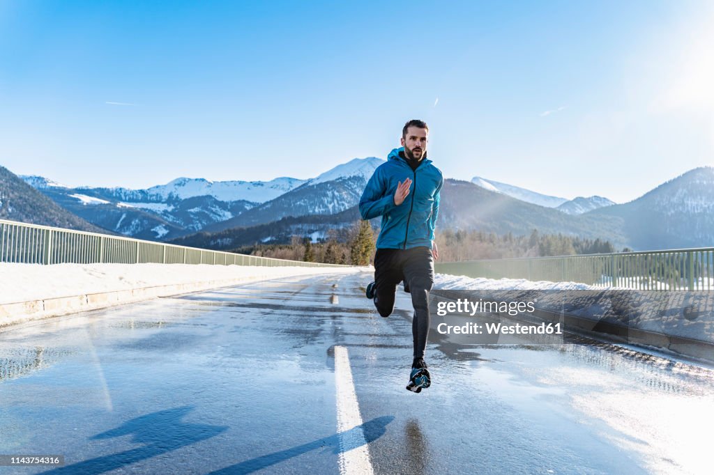 Germany, Bavaria, sportive man running on a road in winter