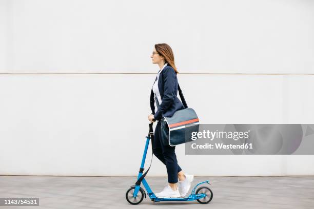 active businesswoman riding scooter in the city - crossbody bag 個照片及圖片檔