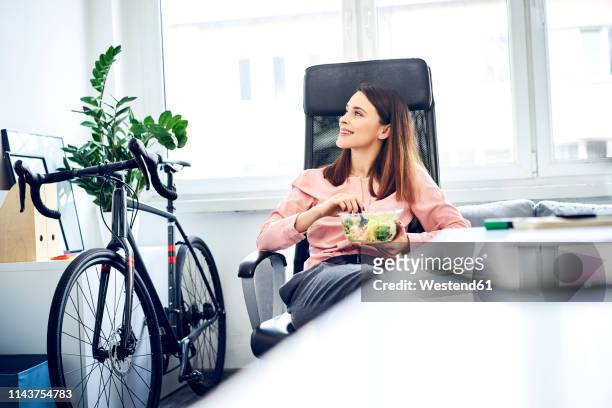 businesswoman having lunch break in office sitting at desk - lunch lady foto e immagini stock