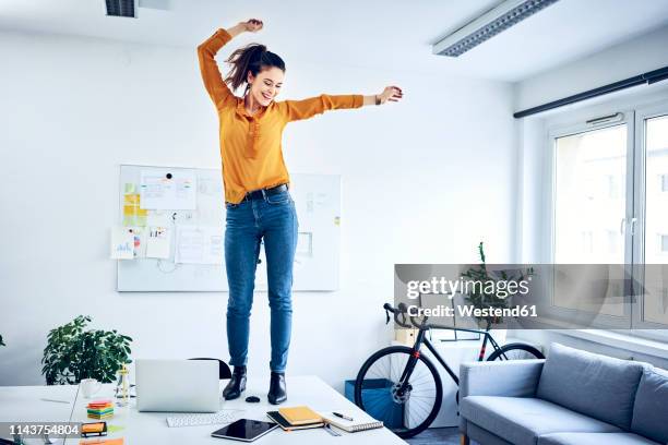 happy young businesswoman cheering in office - champion bureau photos et images de collection