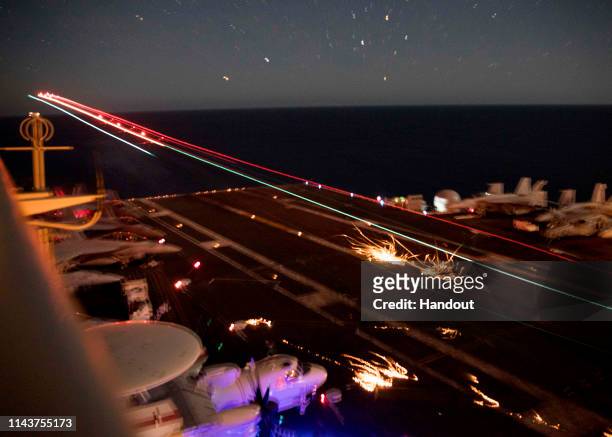 In this handout photo provided by the U.S. Navy, an F/A-18E Super Hornet lands on the flight deck of the Nimitz-class aircraft carrier USS Abraham...