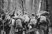 Re-enactors Dressed As World War II Russian Soviet Red Army Soldiers Marching Through Forest In Autumn Day. Photo In Black And White Colors. Soldier Of WWII WW2 Times