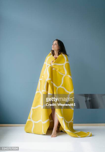 woman standing in front of blue wall, wrapped in yellow rug - yellow carpet stock pictures, royalty-free photos & images