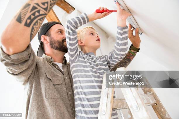 father and son working on loft conversion using water level - attic conversion stockfoto's en -beelden