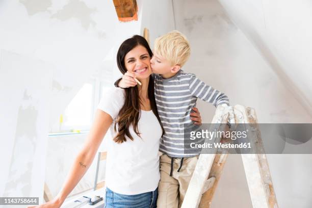 portrait of happy mother and son working on loft conversion - attic conversion stockfoto's en -beelden