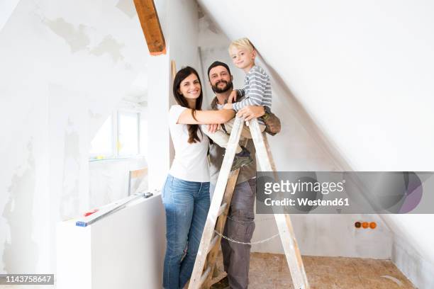 portrait of happy family working on loft conversion - attic conversion stockfoto's en -beelden