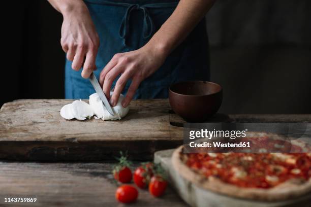 young man preparing pizza, cutting mozzarella on chopping board - モッツァレラチーズ ストックフォトと画像