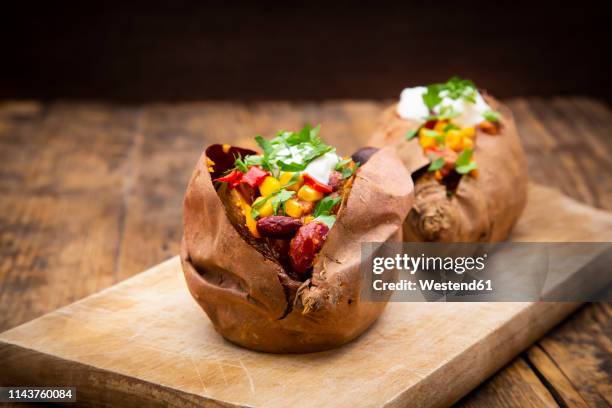 sweet potato kumpir with chili con carne, sour cream and coriander - gepofte-aardappel stockfoto's en -beelden