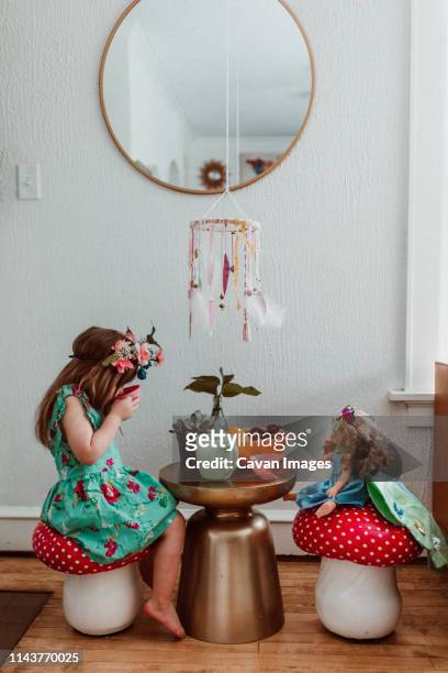 little girl and doll having a tea party at home with flowers - american girl doll stock pictures, royalty-free photos & images