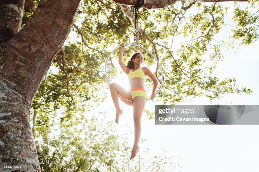 Young African American Woman Training With Aerial Hoop Hanging on Tree