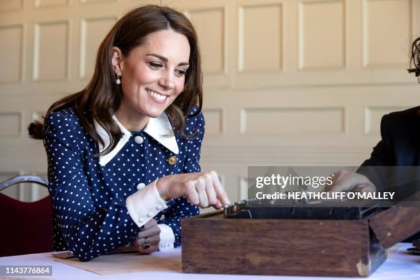 Britain's Catherine, Duchess of Cambridge, reacts as she uses an Enigma cipher code machine during her visit to Bletchley Park in Bletchley, north...