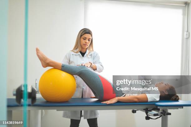 physiotherapist supporting woman exercising with rehabilitation ball - human spine stock pictures, royalty-free photos & images