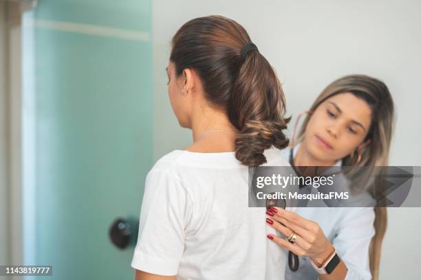 doctor checking patient's heart with stethoscope at a hospital - doctor listener imagens e fotografias de stock