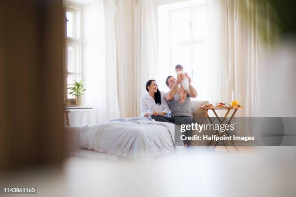 young couple in love with a baby on bed in the morning at home, eating breakfast. - asian young family bildbanksfoton och bilder