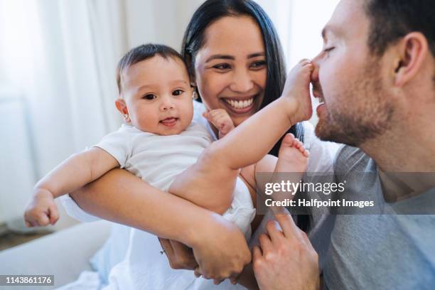 affectionate young couple in love with a baby at home, resting. - asian mom kid kiss stock-fotos und bilder