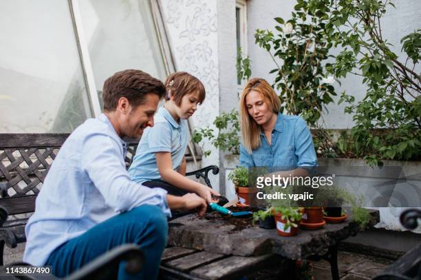 Family Planting Herbs On Their Balcony